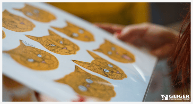 A woman holding a piece of artwork that has cats on it